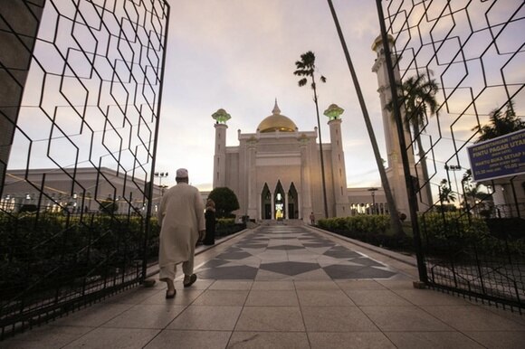 Una moschea vista dal cancello all inizio del viale d ingresso; un uomo cammina in direzione di essa