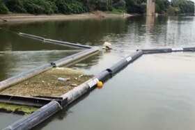 Immagine di un fiume, sul filo dell acqua del quale sono posati dei tubi galleggianti a mo di barriera