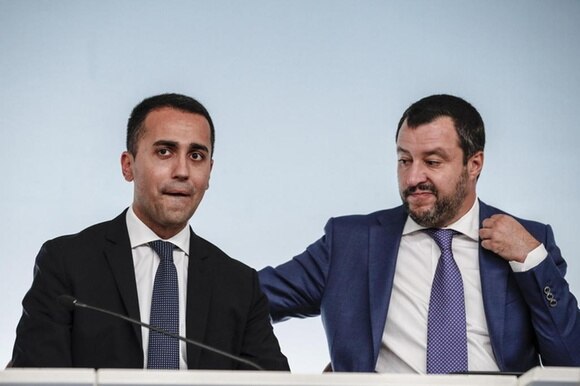 Primo piano di Luigi di Maio e Matteo Salvini seduti a un tavolo durante una conferenza stampa.