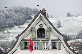 Casa alle cui finestre sono esposte due bandiere.