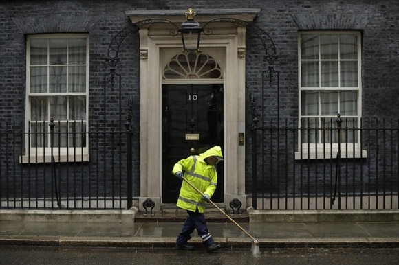 Uno spazzino vestito di giallo pulisce la strada davanti al 10 di Downing Street a Londra, sede del primo ministro inglese
