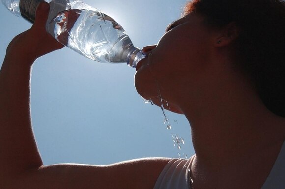 una persona mentre beve da una bottiglia d acqua
