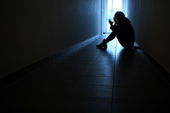 persona seduta per terra in un buio corridoio