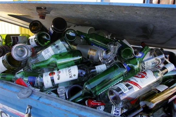 Bottiglie di vetro in un ammassate in un contenitore per il riciclaggio