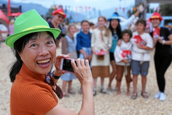 donna sorride mentre fotografa un gruppo