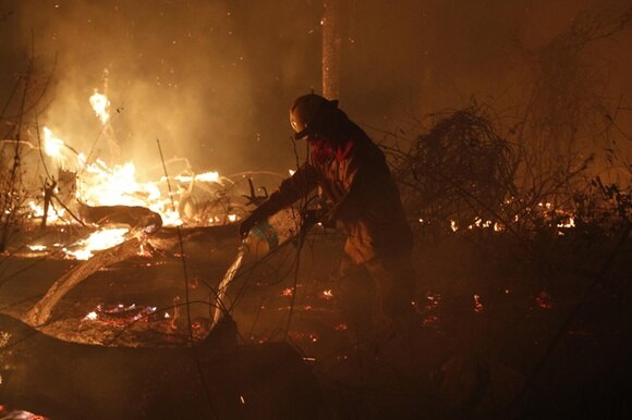 Un pompiere circondato dal fuoco nella foresta amazzonica