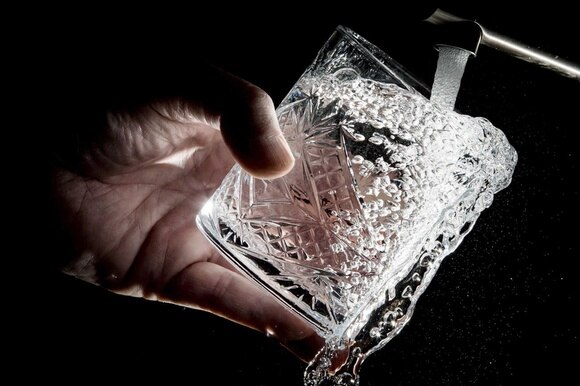 acqua sgorga da un rubinetto in un bicchiere
