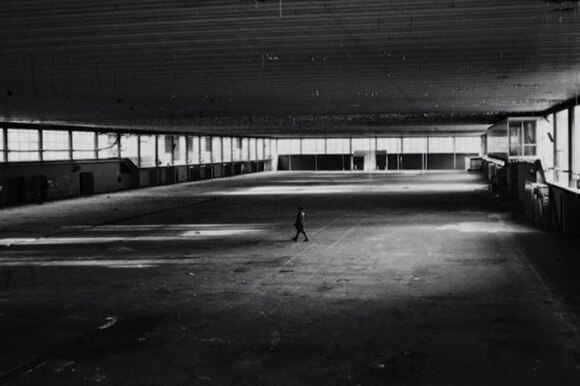 Un fotogramma del documentario: il regista piccolo piccolo in un capannone industriale completamente vuoto e fatiscente