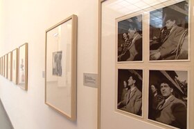 Piccoli ritratti fotografici montati su passepartout ed esposti in cornici su pareti bianche di un museo
