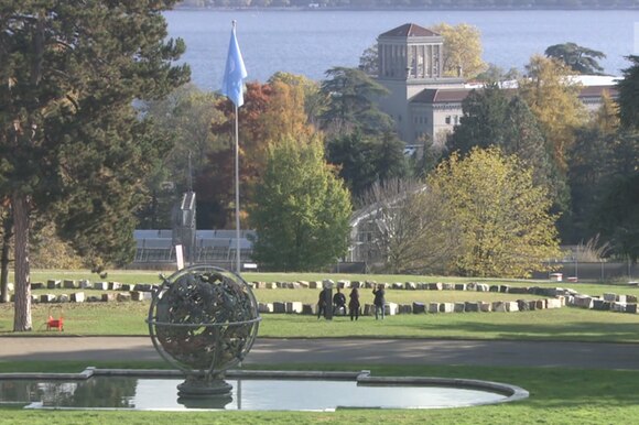 Veduta di un parco in riva al lago con grandi edifici, una bandiera dell Onu e la scultura di un globo