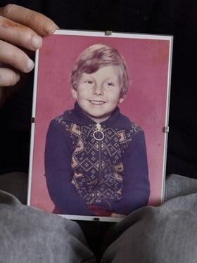 foto di un bambino, risalente agli anni 70, riflettuta allo specchio.
