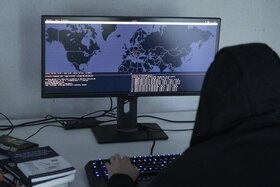 Una persona incappucciata davanti a uno schermo di un computer.