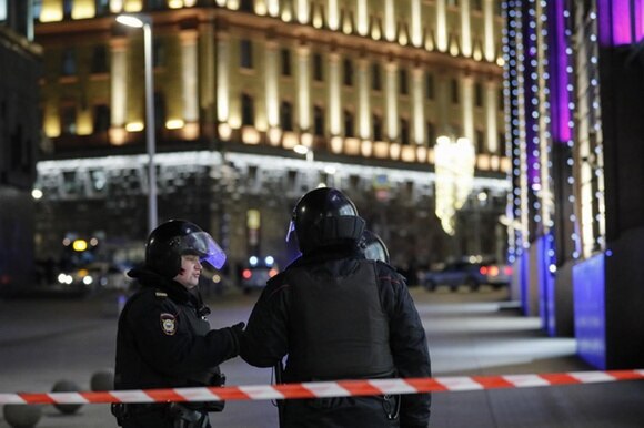 Due poliziotti in tenuta antisommossa poco oltre un nastro di delimitazione in un centro città con luminarie natalizie