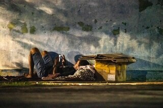 Obdachloser mit Handy am Boden liegend.