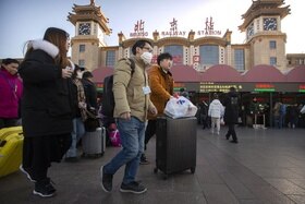 Piazzale antistante la stazione (ferroviaria) centrale di Pechino; viaggiatori indossano mascherina sanitaria
