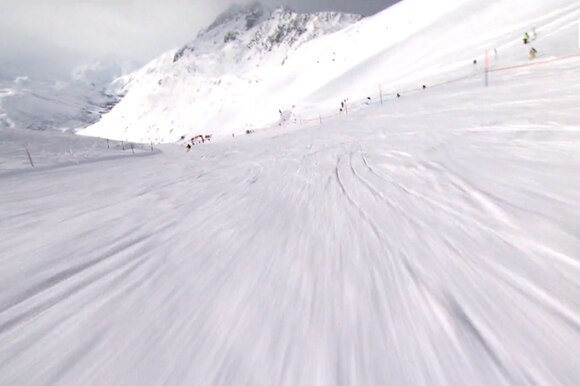Ripresa in soggettiva di uno sciatore che percorre a tutta velocità una pista da sci; in lontananza, skilift