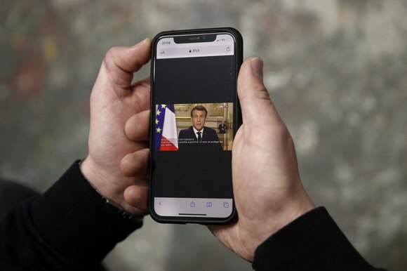 Un cittadino francese che guarda l annuncio di Macron con il telefonino