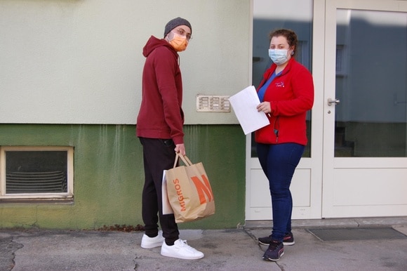 due persone che indossano mascherine protettive all ingresso di un edificio.