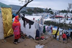 donna davanti a tende di un campo profughi