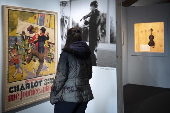 Ambienti di museo, esposti: un violino, una foto di Chaplin che suona, un manifesto di film.