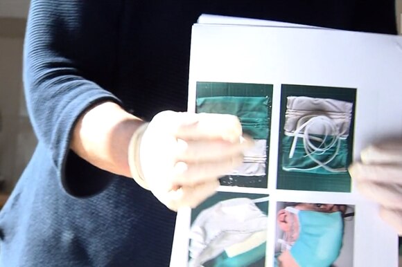 UNa signora con guanti in lattice scuote un mazzo di fogli A4 come per allinearli; si vedono immagini di mascherine chirurguche