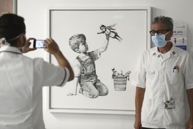 Un medico on mascherina posa davanti all opera di Banksy
