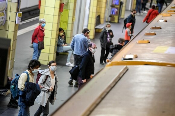 Viaggiatori con mascherina salgono su un convoglio ferroviario