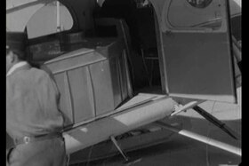 Lato di un aereo con portellone aperto e una grossa tanica all interno; si intravvede uomo in uniforme