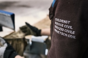 Persona con giacca con la scritta Servizio civile in quattro lingue.