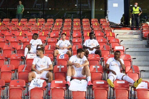 Giocatori dello Zurigo seduti in tribuna con la giusta distanza.