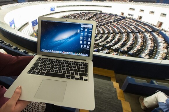 Primo piano di un MacBook Air sulle ginocchia di una persona seduta tra il pubblico nel Parlamento europeo di Strasb
