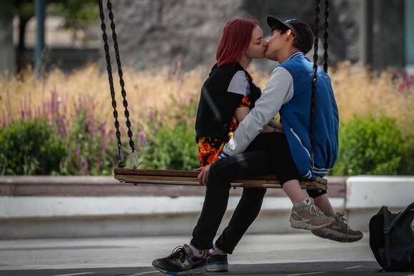 una giovane coppia che si bacia seduti su un altalena.
