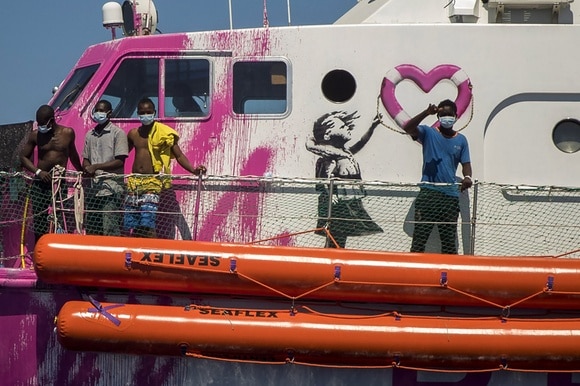 Migranti a bordo della Louise Michel, nave umanitaria dipinta e finanziata da Bansky.