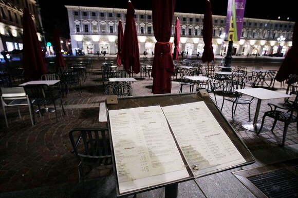 Primo piano di un leggio con un menu all esterno di un ristorante in una piazza di città con colonnato