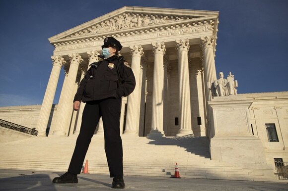 Colonnato dell edificio della Corte Suprema USA al tramonto, presidiata da un poliziotto