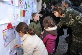 Bmbini che appendono i loro disegni a una parete per solidarietà della scomparsa di una loro amica.