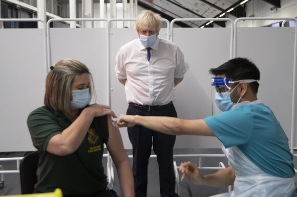 Il premier Johnson mentre guarda vaccinare una ragazza in uno dei centri per le vaccinazioni del Regno Unito