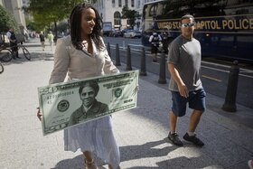La rappresentante del Massachusetts Ayanna Pressley con in mano una gigantografia della banconota da 20 dollari