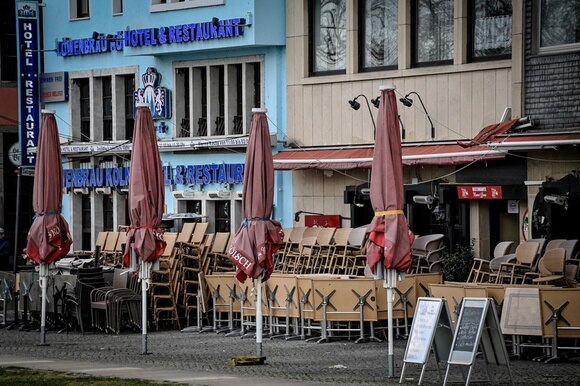 Vista trasversale di alcuni locali tedeschi (lo si desume dalle scritte) con serrande giù, ombrelloni chiusi e sedie accatastate
