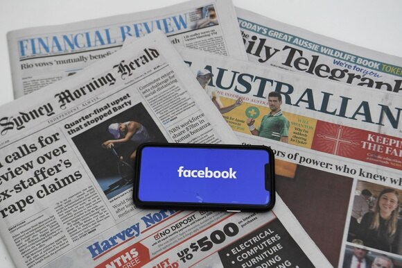 Un telefonino con l app di Facebook sopra diversi quotidiani australiani.
