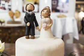 Una coppia di sposi in marzapane su una torta nuziale.