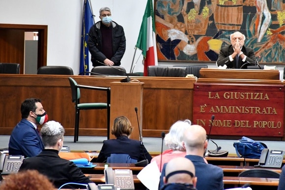 Aula di tribunale con giudice a mani conserte e Salvini di profilo; Bongiorno di schiena