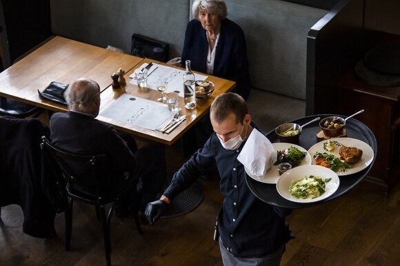 cameriere e due persone sedute a un tavolo di un ristorante