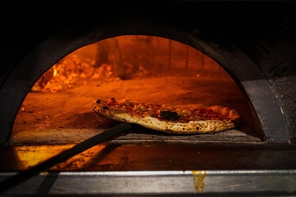 Una pizza mentre viene infornata in un forno a legna a Napoli.