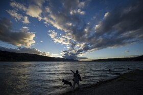 lago al tramonto, signora gioca con il cane in riva