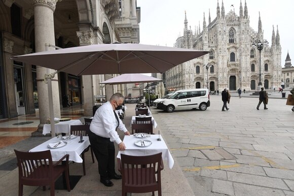 Cameriere prepara i tavoli del suo ristorante in Piazza Duomo a Milano.