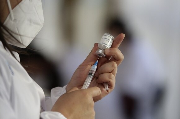 donna con mascherina preleva con una siringa vaccino da una fiala