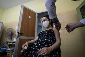 donna incinta con visiera e mascherina si fa vaccinare
