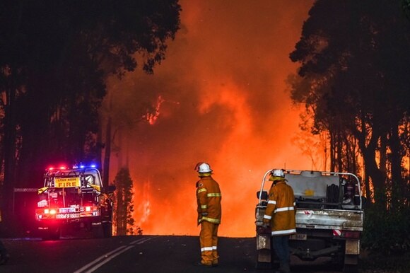 Un incedio scoppiato a inizio febbraio in Australia: si vedono due pompieri con due autoveicoli e l incendio.