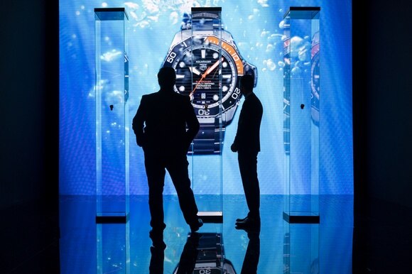 Due persone davanti a orologi in esposizione in colonne di vetro